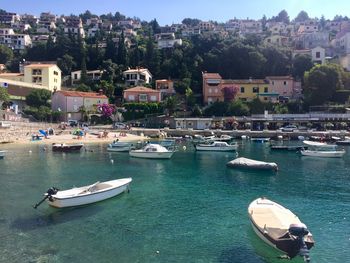 Sailboats moored in sea against buildings in city