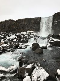Scenic view of waterfall against sky during winter
