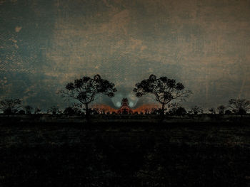 Trees on field against sky at dusk
