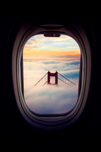 Golden gate bridge amidst cloudscape seen through airplane window