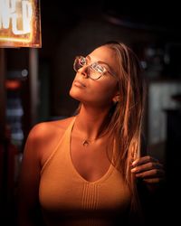 Beautiful woman wearing eyeglasses looking away while standing in darkroom