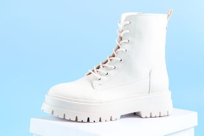 One pair of white demi-season boots made of eco-leather with buckles and laces stand on a white box