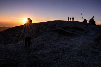 Rear view of silhouette people walking on land during sunset