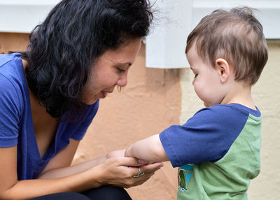 Cute little toddler is playing pebbles with mom on the back porch