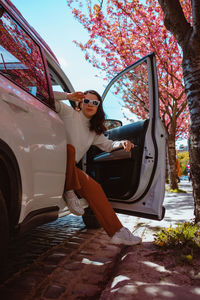 Portrait of young woman sitting on car