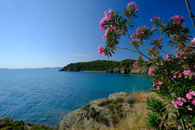 Scenic view of sea and mountains against clear blue sky