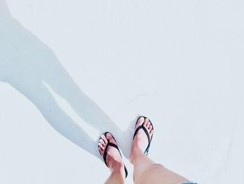 Low section of woman standing at sandy beach