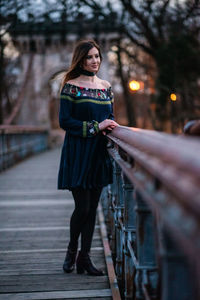 Full length portrait of woman standing on footbridge