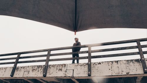Low angle view of man standing by railing
