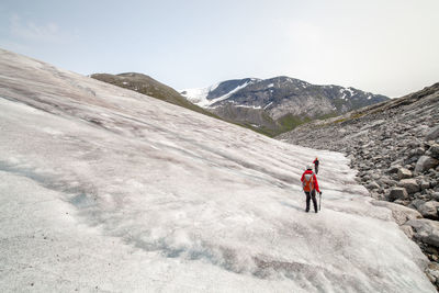 Rear view of people hiking on mountain during winter