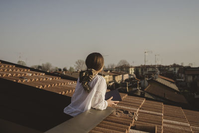 Woman standing on terrace against clear sky