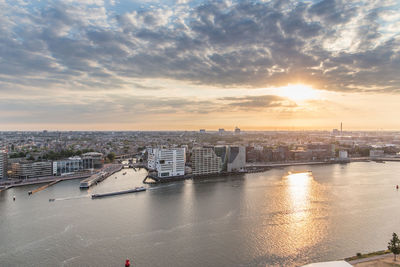 Aerial view of city against cloudy sky during sunset