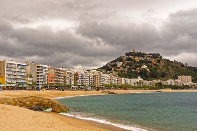 View of houses on beach against cloudy sky