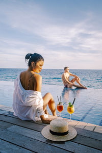 Woman sitting on pier at poolside