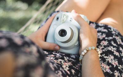 Midsection of woman holding camera