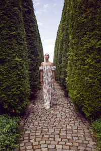 Outdoor portrait of a beautiful luxury brunette woman in a dress with flowers stands in a park