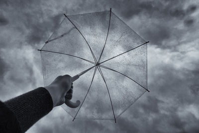 Close-up of man holding umbrella against sky