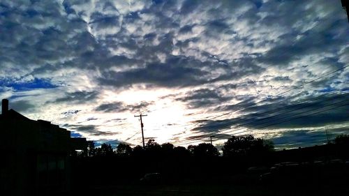 Silhouette trees against cloudy sky