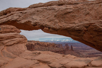 Full frame close-up view of mesa arch with snow capped mountains in the background