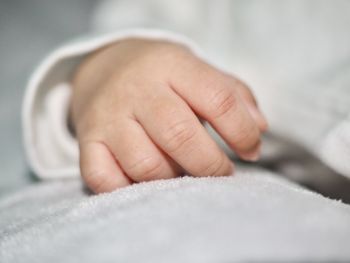 Close-up of baby hand on bed