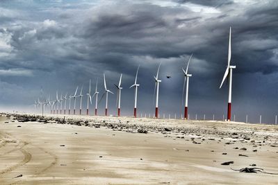 Wind turbines on beach against sky