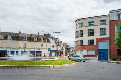 Buildings by road against sky in city