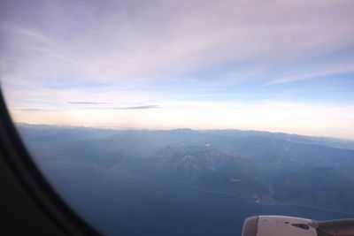 Scenic view of mountains against sky seen through airplane window
