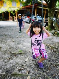 Portrait of smiling cute girl swinging outdoors