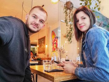Portrait of young couple sitting on table at restaurant