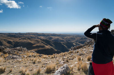 Rear view of man photographing on mountain against sky