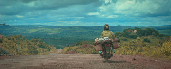 Rear view of man riding scooter against sky