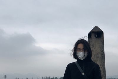 Portrait of young woman standing against sky