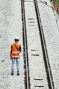 Rear view of worker standing by railroad track