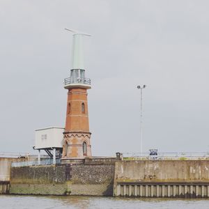 Lighthouse by sea against sky