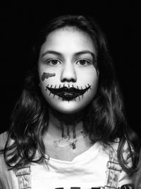 Portrait of girl with halloween make-up against black background