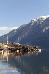 Buildings by lake against sky during winter