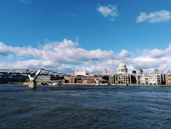 View of buildings by sea against cloudy sky