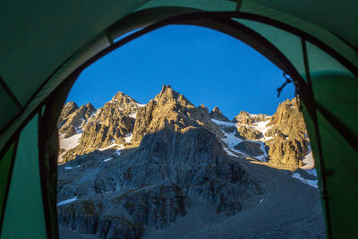 Snowcapped mountains seen through tent against clear sky