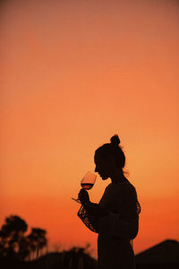 Side view of man photographing against sky during sunset