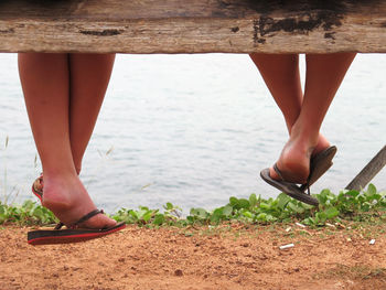 Low section of woman sitting on bench against lake