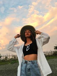 Low angle view of woman wearing hat against sky