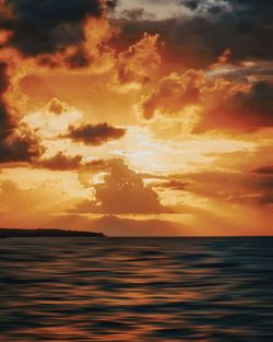 Scenic view of sea against dramatic sky during sunset