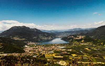 Aerial view of townscape and mountains against blue sky