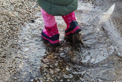 Low section of child walking in puddle