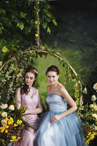 Smiling females sitting on decorated swing