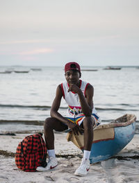 Full length of man sitting at beach against sky