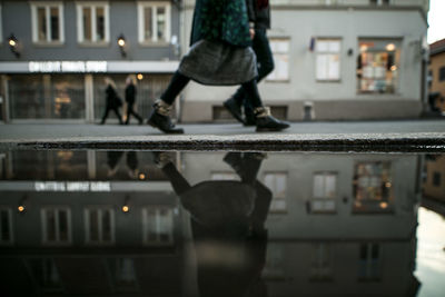 Low section of woman reflecting in puddle