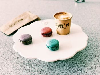 Macaroons with coffee on tray at table