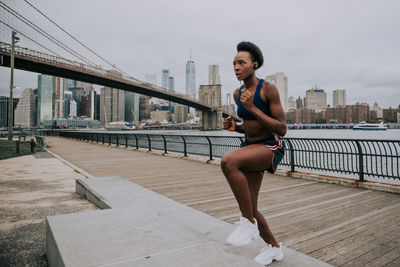 Woman exercising on bridge in city