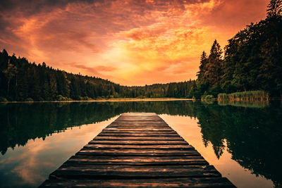 Pier over lake against sky during sunset